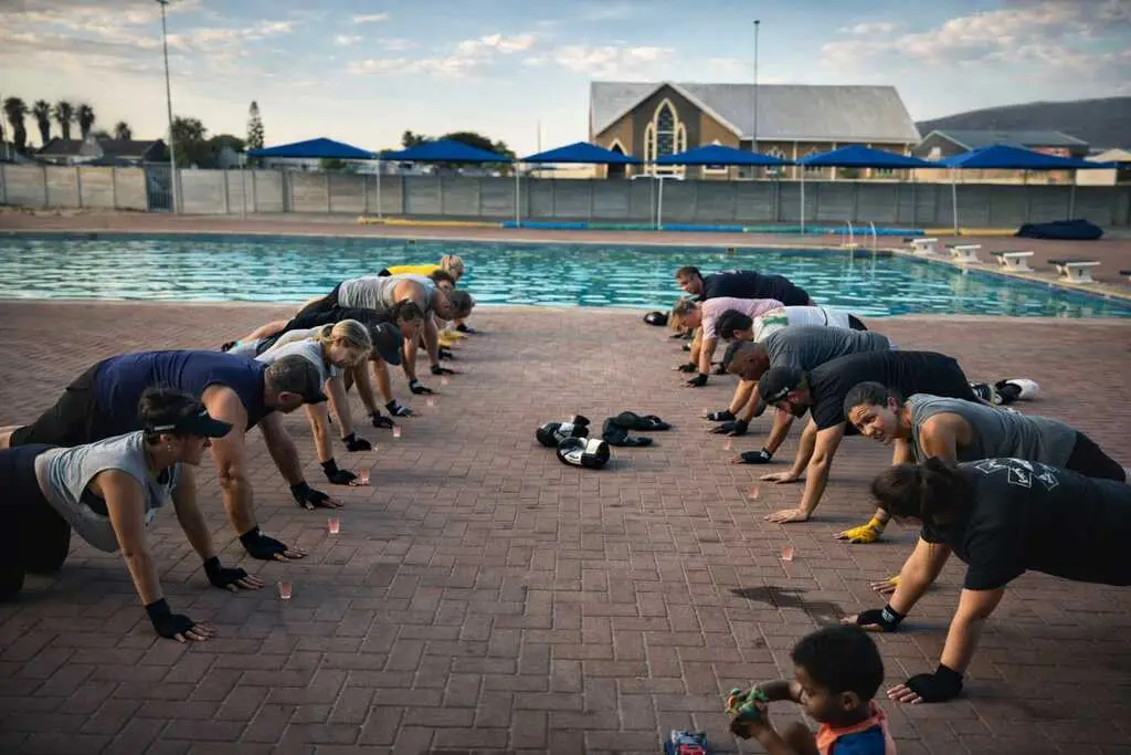 Row of members doing push-ups beside the pool