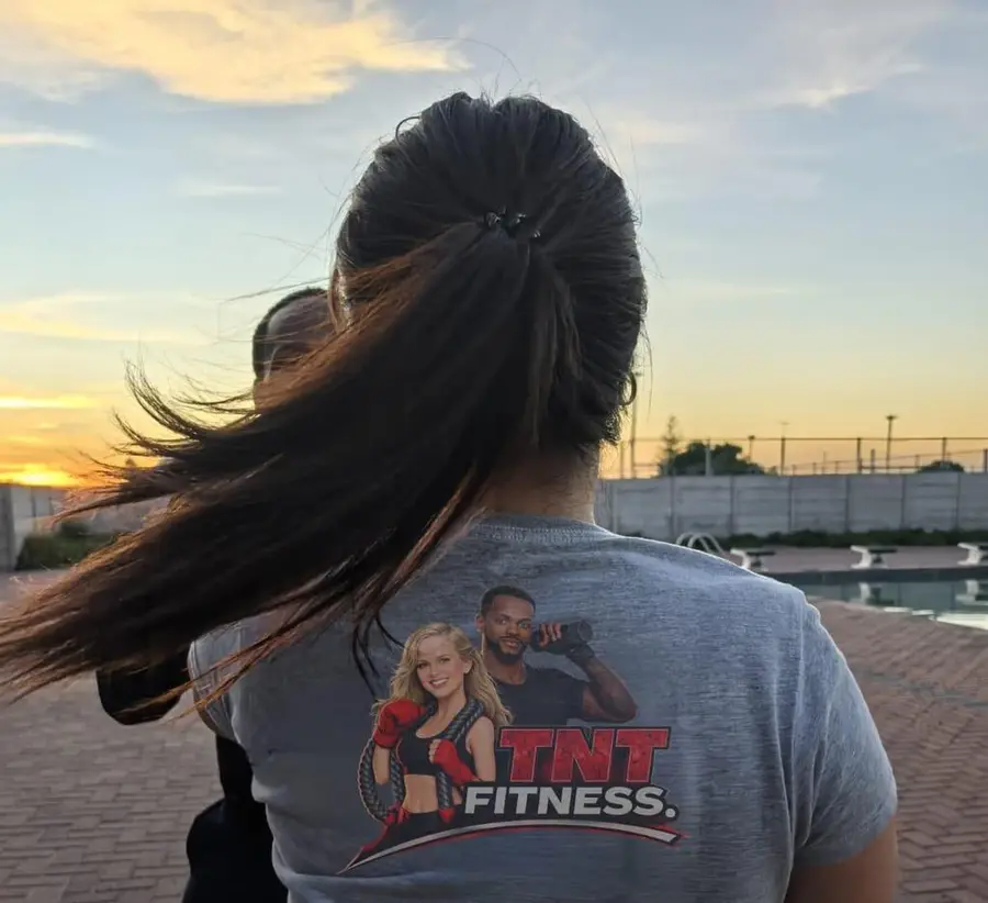 TNT member in a TNT Fitness shirt at sunrise