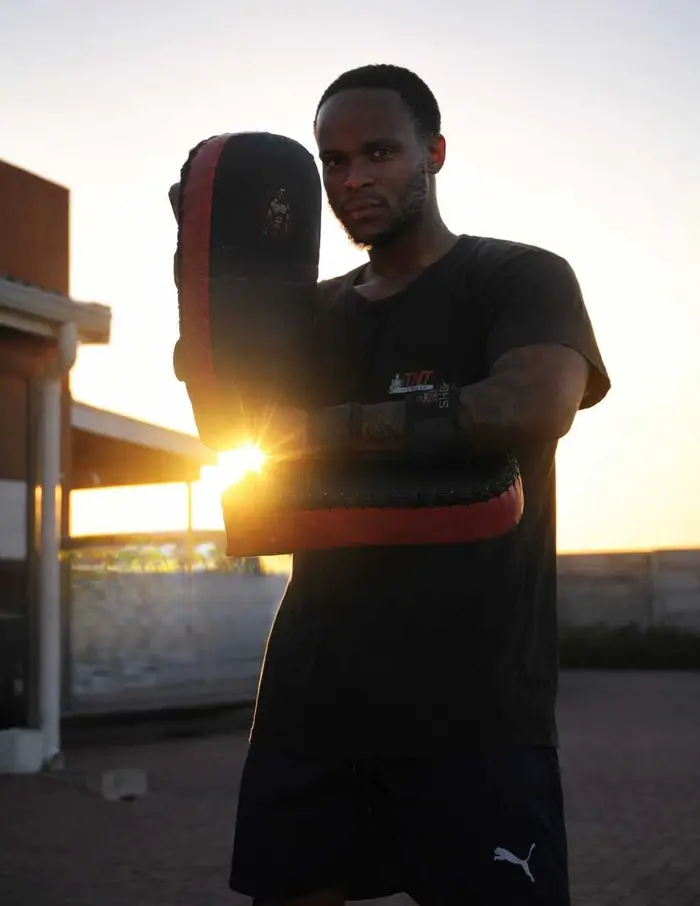 Coach Yams holding a kick shield at sunset